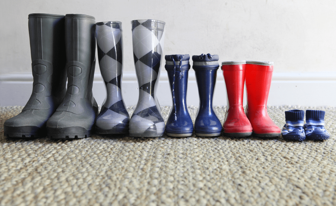 Botas de adultos e crianças lado a lado, representando a família